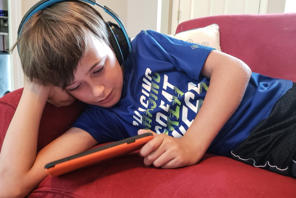 Boy with headphones lying on couch with tablet 2026 03 19 02 17 10 utc